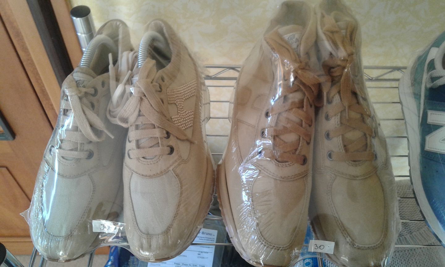 Tre paia di scarpe sono avvolte nella plastica e appese a uno scaffale.