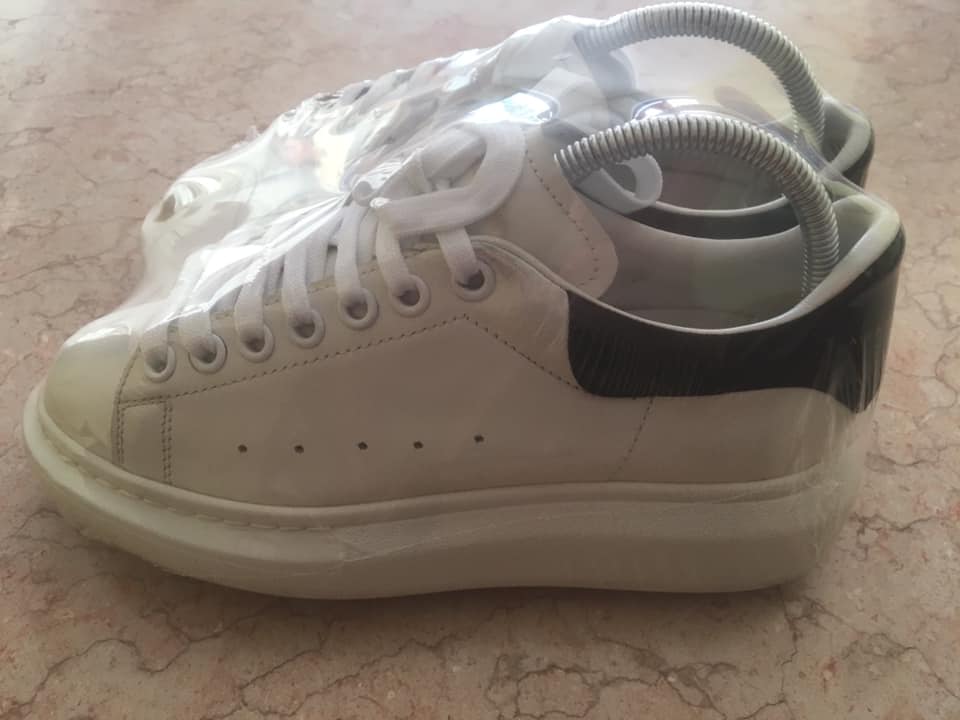 Un paio di scarpe da ginnastica bianche con la suola nera sono avvolte nella plastica.