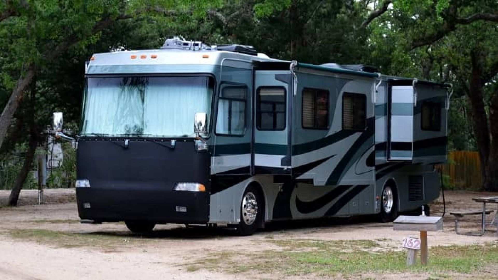 A large rv is parked in a dirt lot.