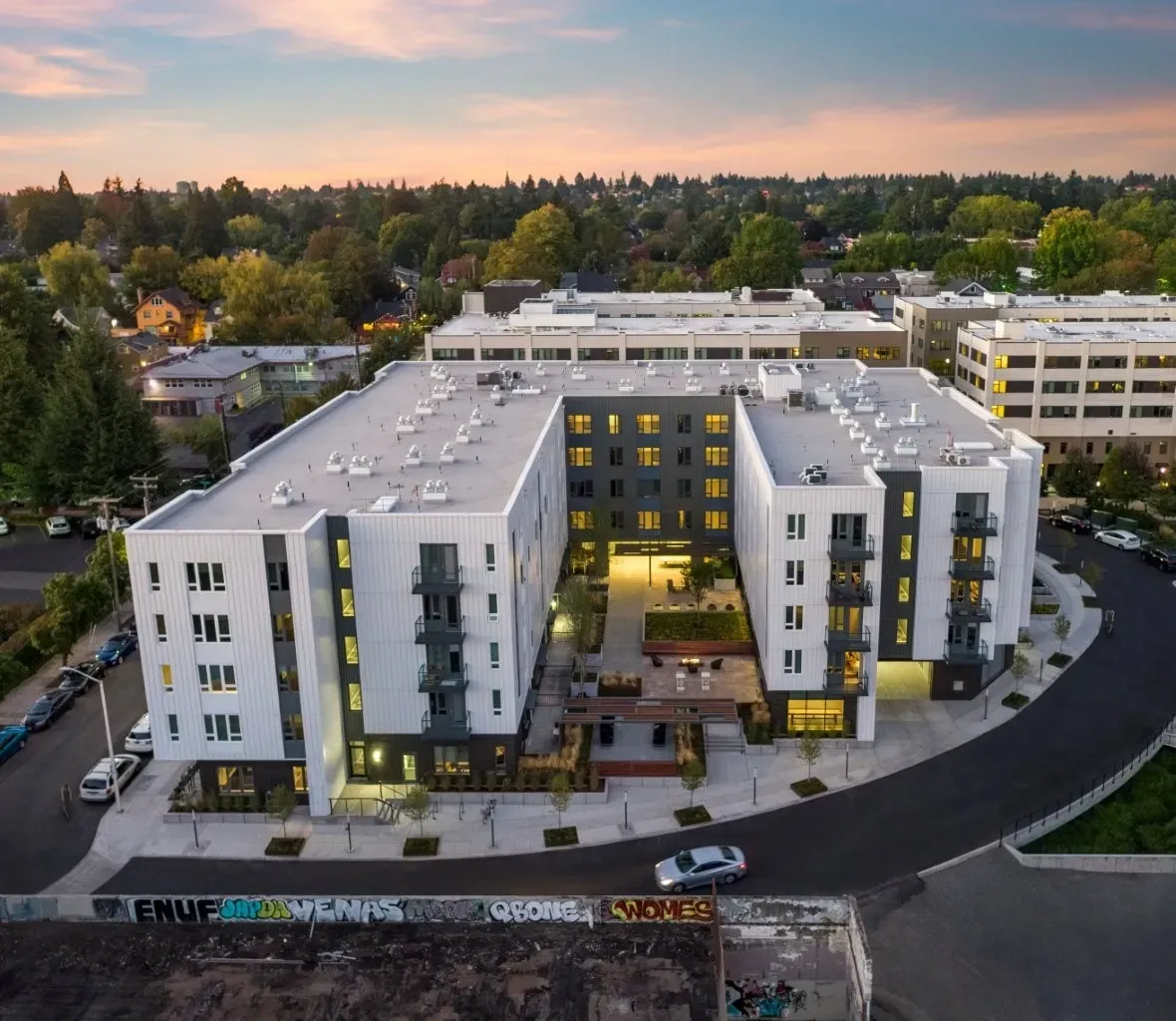A modern building with a curved design is surrounded by a parking lot.