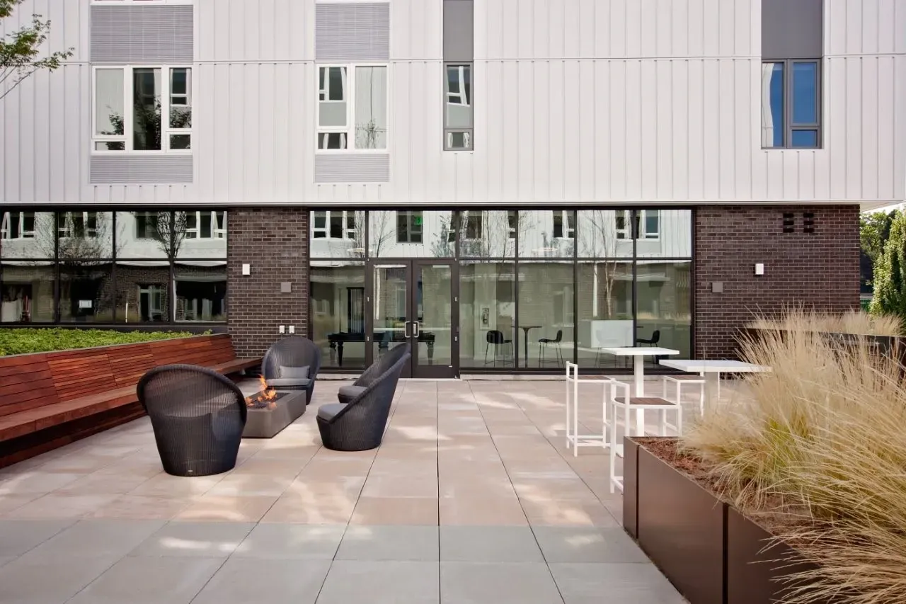 A modern building with a glass facade and a patio with chairs and tables.