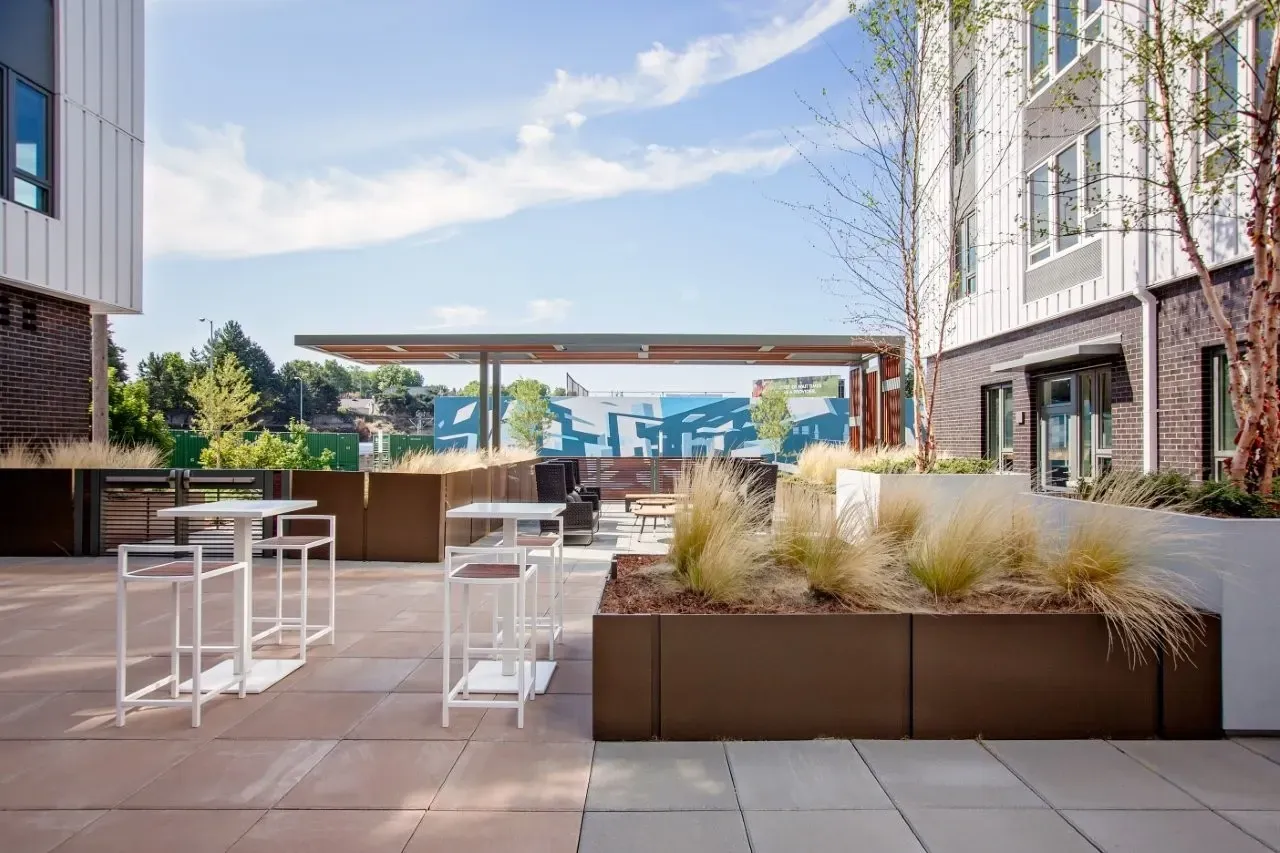 Modern outdoor patio with high-top tables and seating under a covered pergola.