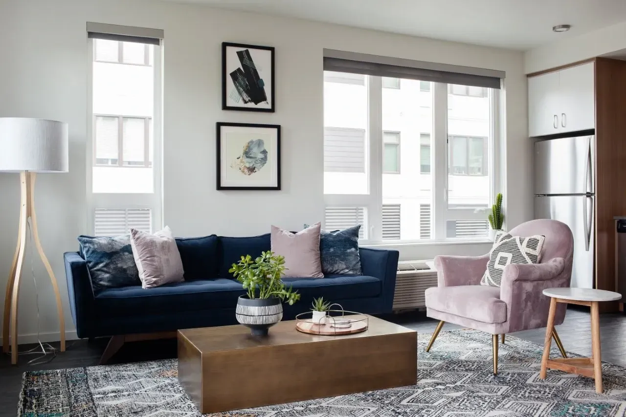 A living room with a blue couch, a pink chair, and a wooden coffee table.