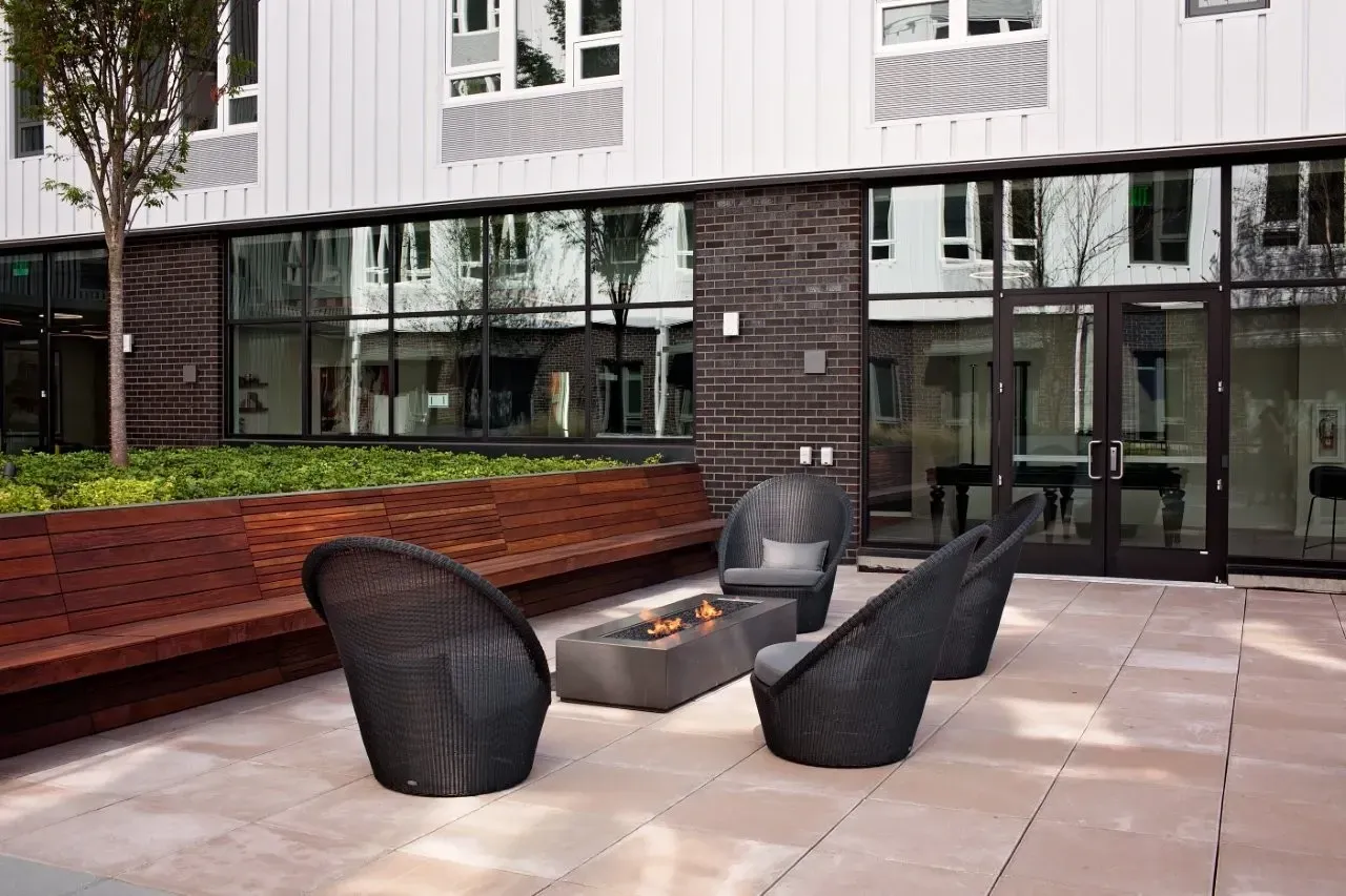 A patio with a fire pit and chairs.