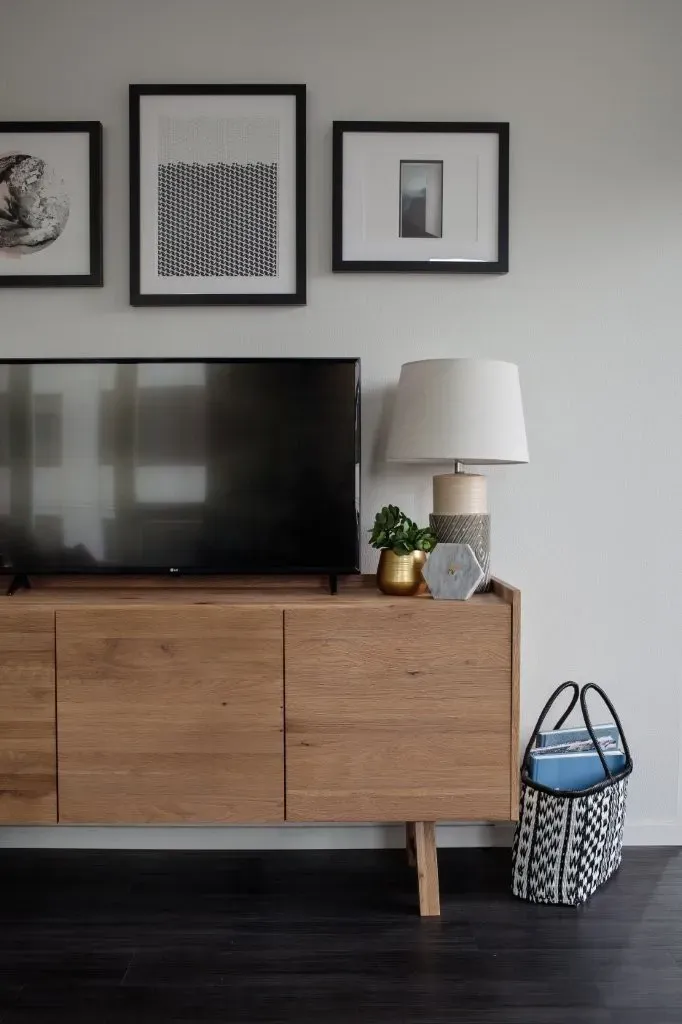 A wooden dresser with a lamp and a plant on top of it.