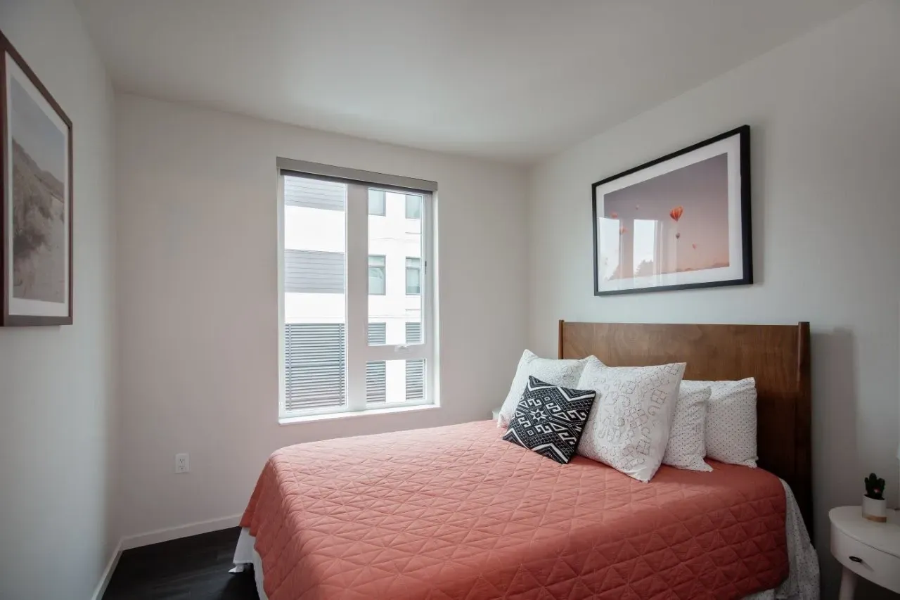 Bedroom with a queen-sized bed, a window, and artwork on the wall.