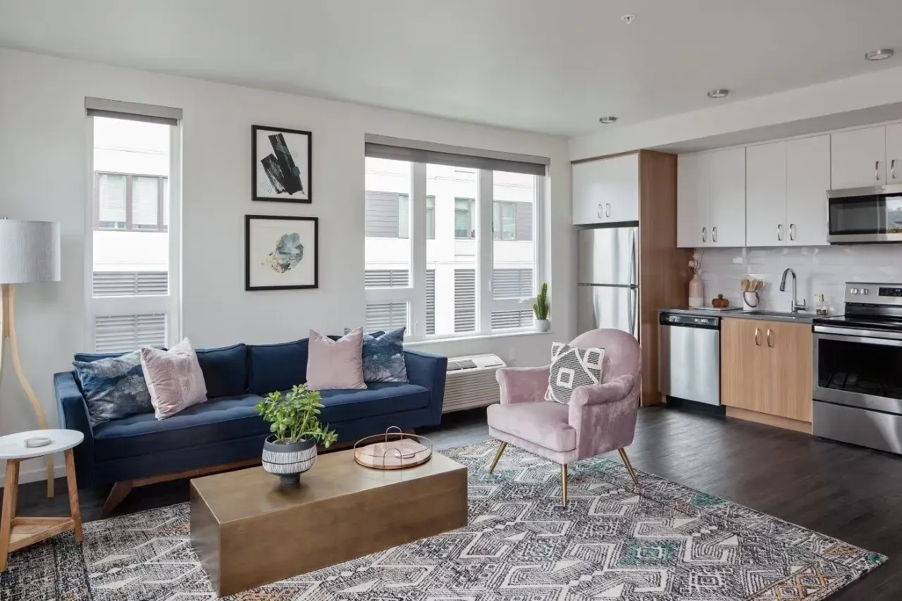 A living room with a blue couch and a pink chair.