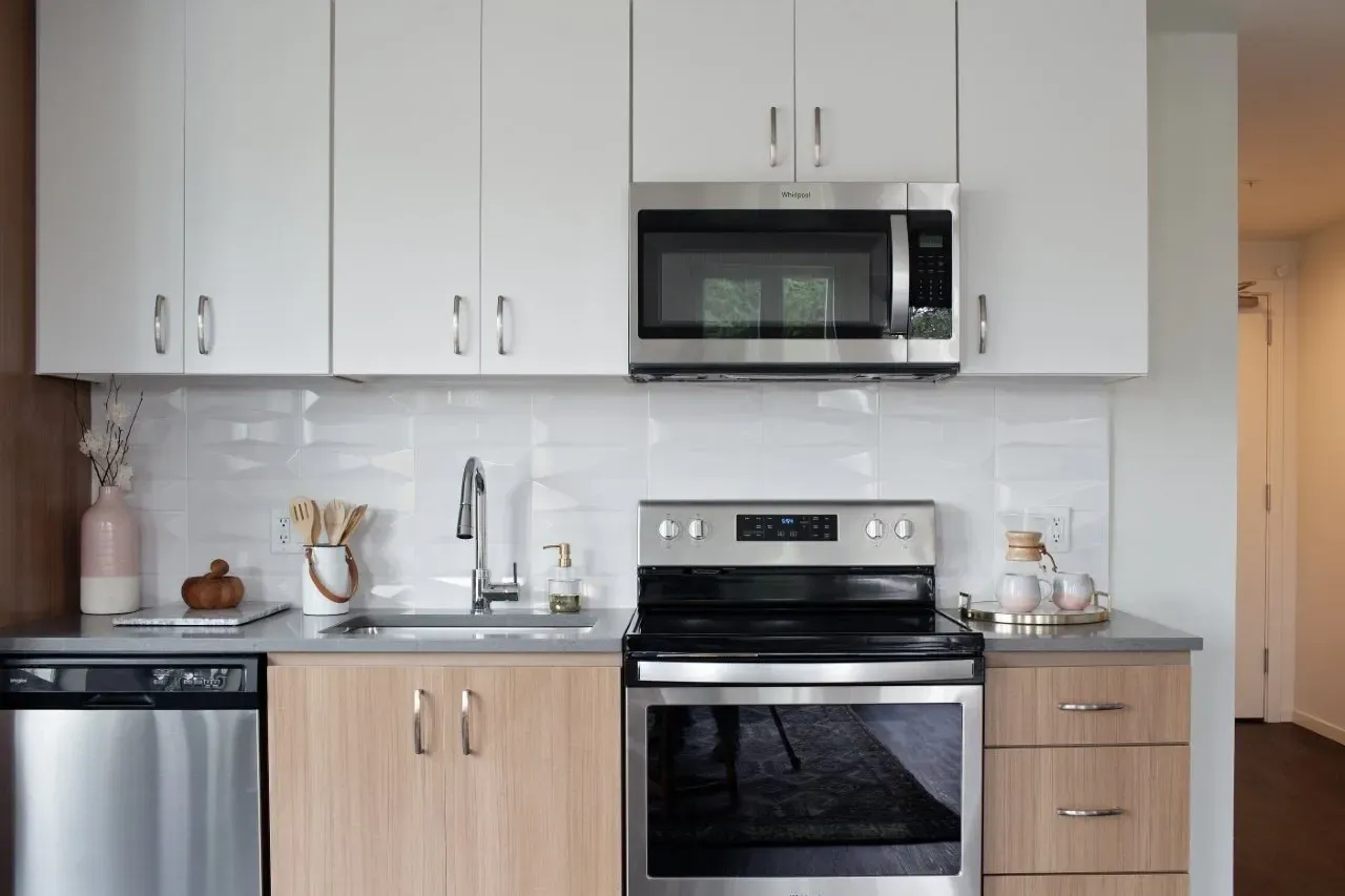 Modern kitchen with stainless steel appliances, white cabinets, and wood accents.
