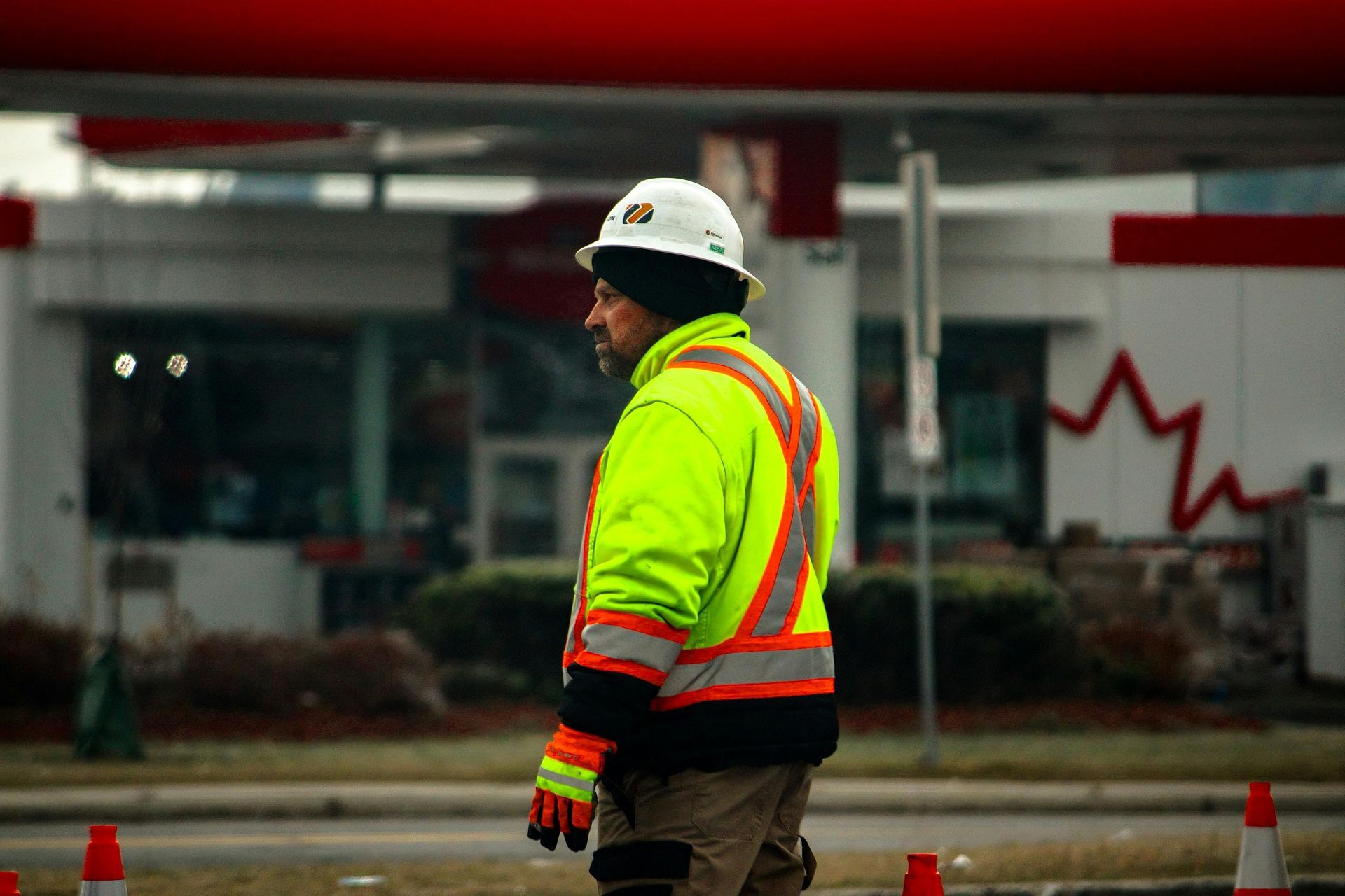 Construction worker in neon safety jacket and hard hat standing outdoors near a building site