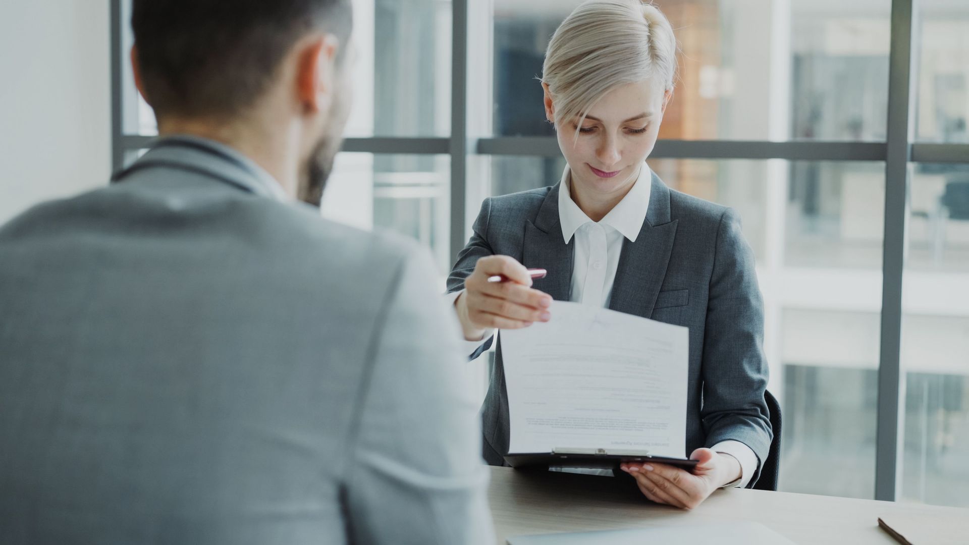 Business meeting with one person signing a document while another sits across the table
