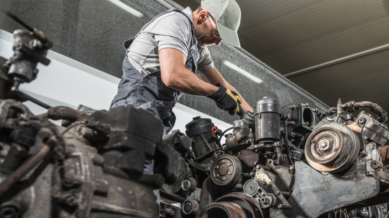 Mechanic working on a large engine in an industrial workshop