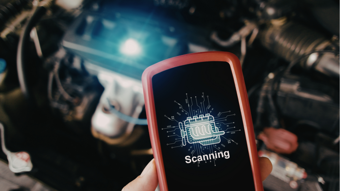 Hand holding a red phone showing “Scanning” in front of a car engine with blue glow