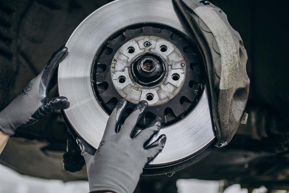 Gloved hands hold a brake rotor and hub assembly during automotive repair
