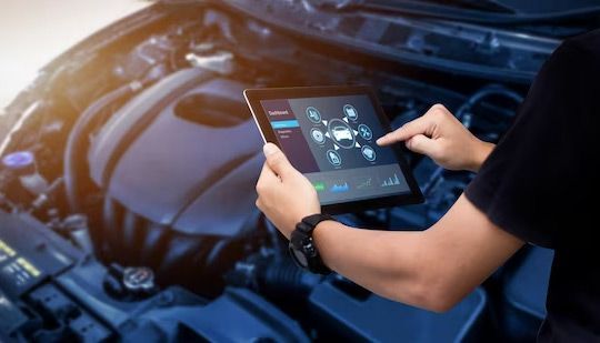 Person using a tablet to diagnose a car engine in a garage