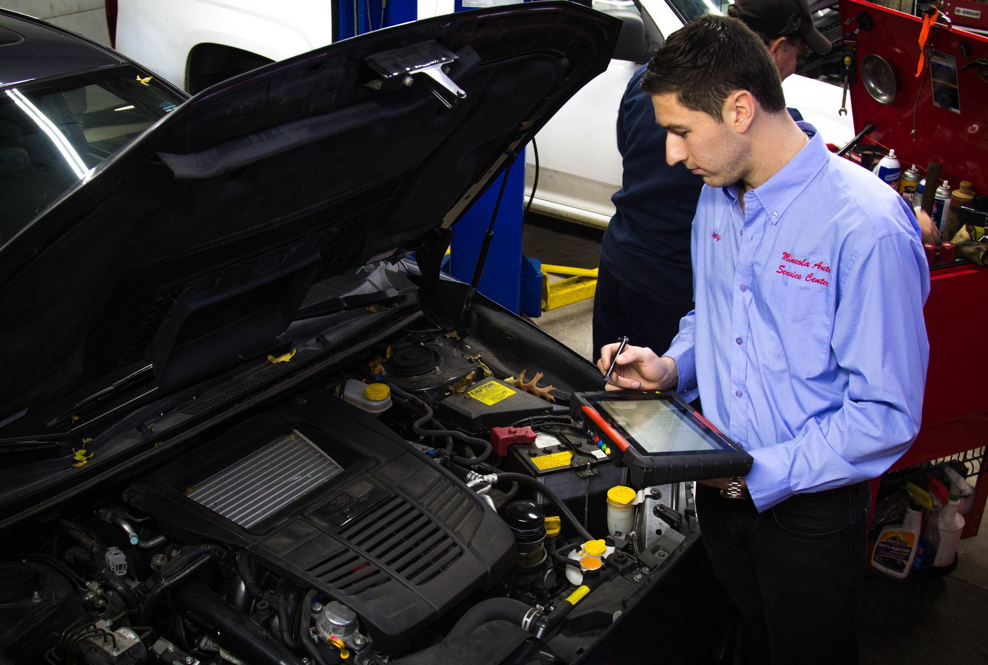 Mechanic inspecting a car engine with the hood open in a repair shop
