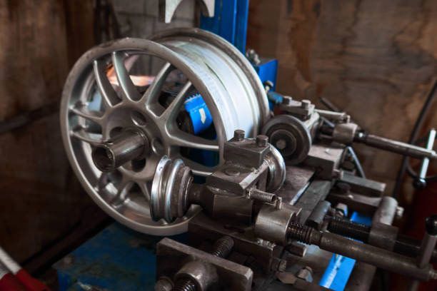 Close-up of a metal lathe with a large wheel and spinning machine parts in a workshop