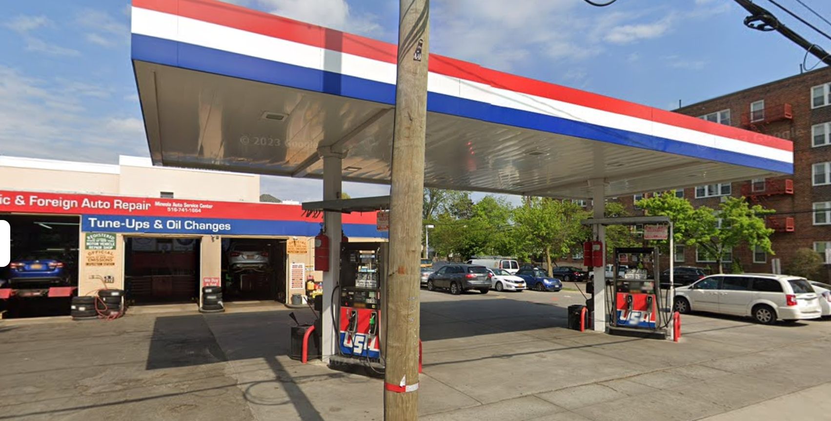 A red white and blue full service gas station with cars parked in front of it