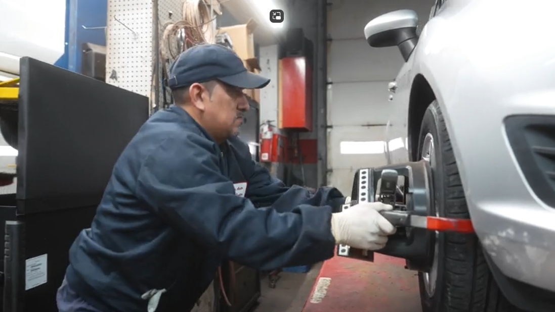 Mechanic using a red tool to service a car tire in a garage
