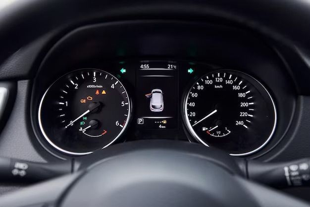Car dashboard with illuminated speedometer, tachometer, and center display showing a door open warning