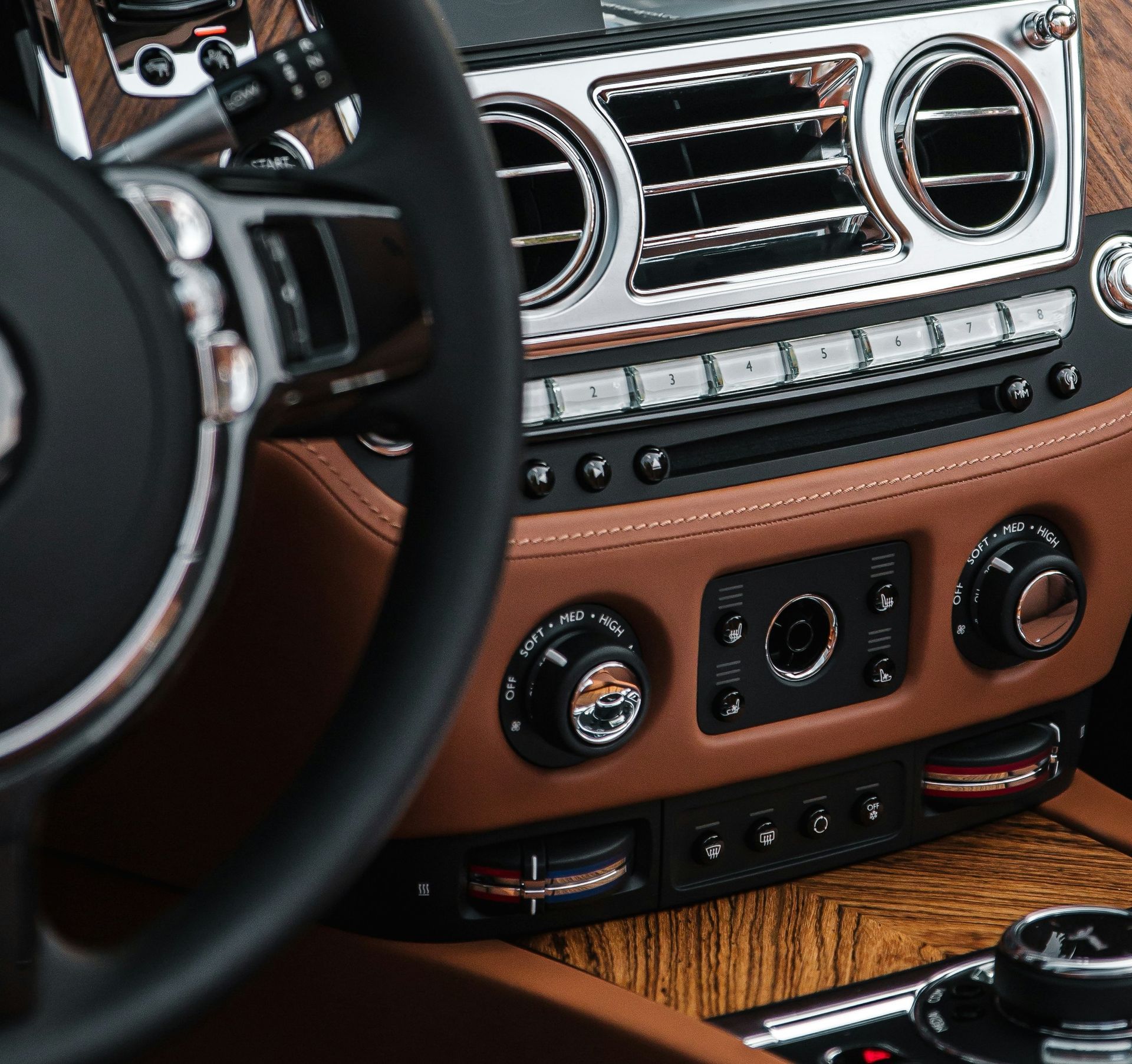 Luxury car dashboard with tan leather trim, chrome vents, and steering wheel view