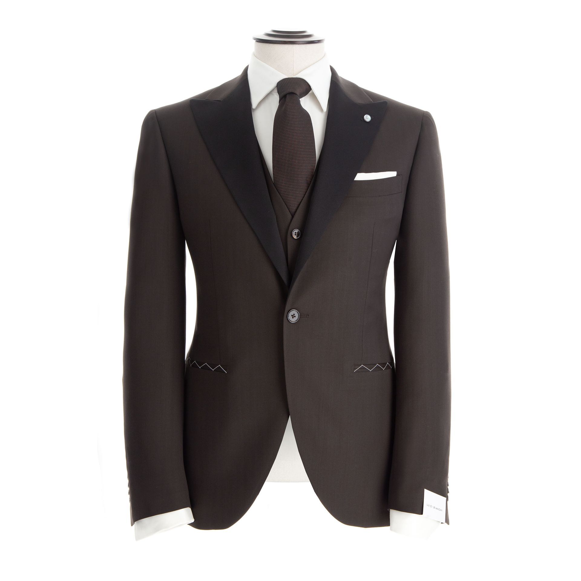 Smoking marrone su manichino con risvolti neri, camicia bianca e cravatta fantasia.