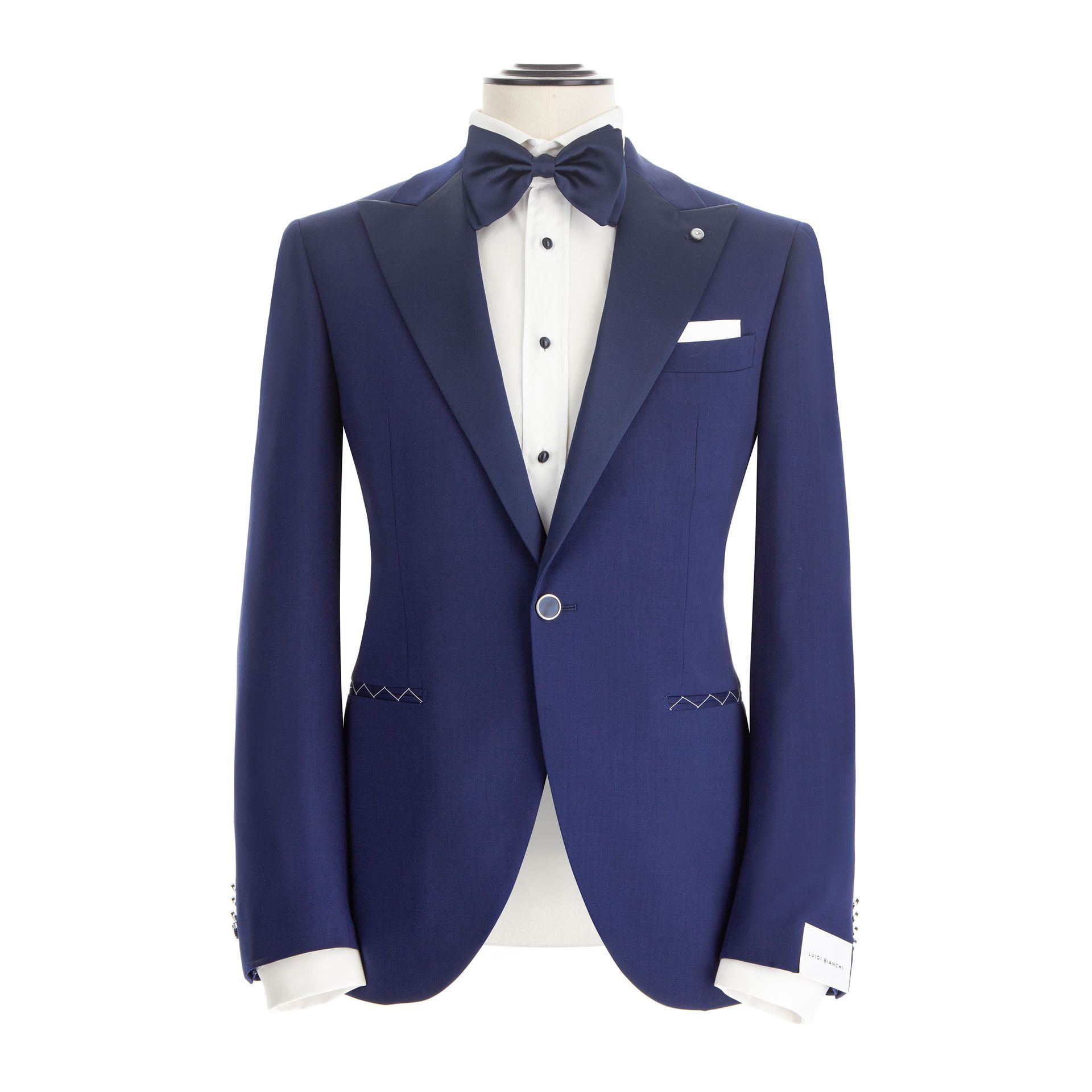 Giacca da smoking blu su manichino, con papillon, camicia bianca e fazzoletto da taschino.