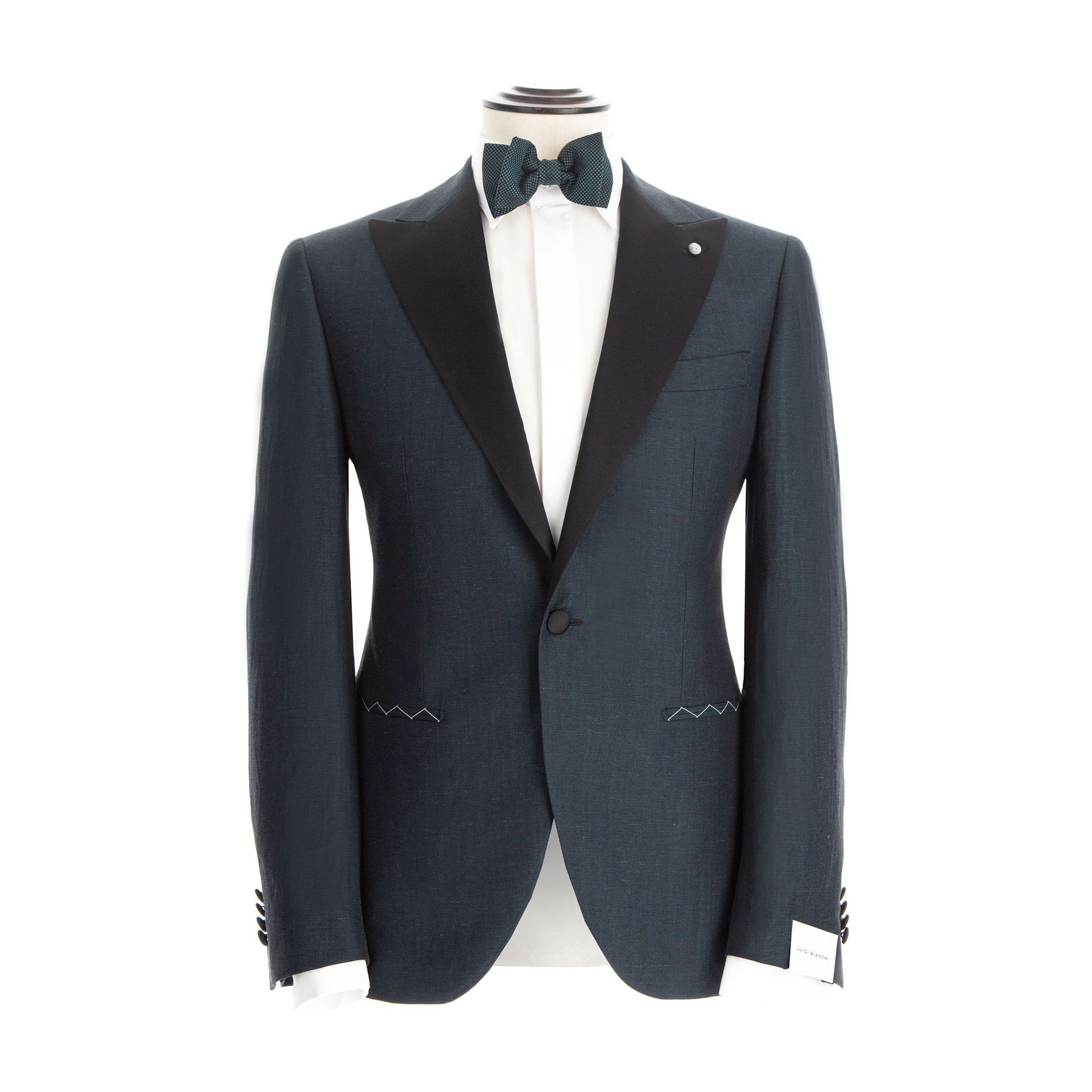 Giacca da smoking blu scuro con risvolto nero, camicia bianca e papillon su un manichino.