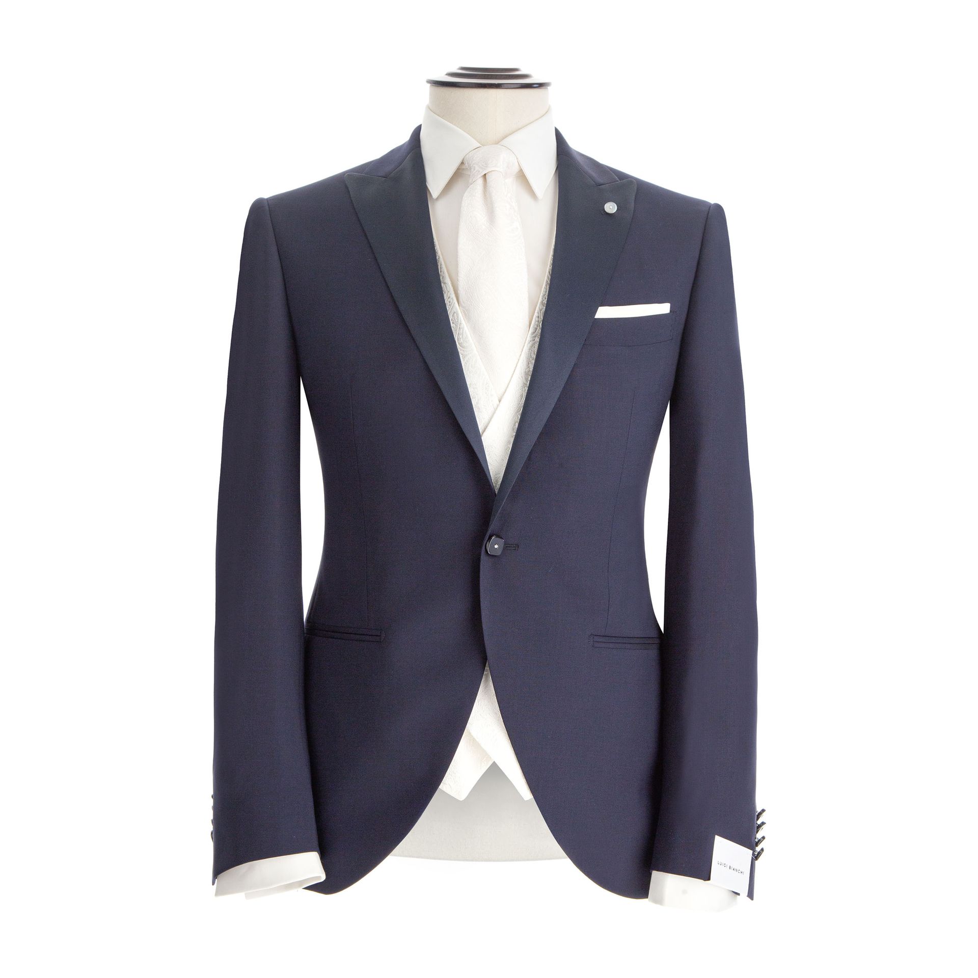 Abito blu navy con camicia bianca, cravatta e fazzoletto da taschino su un manichino.