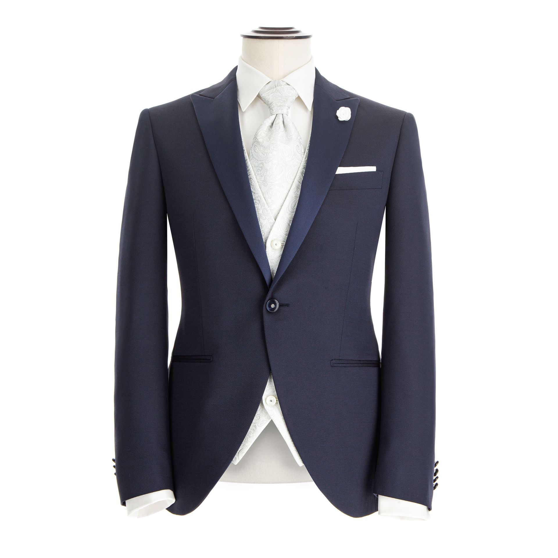 Smoking blu navy su manichino, con gilet e cravatta bianchi. Revers e dettaglio delle tasche visibili.