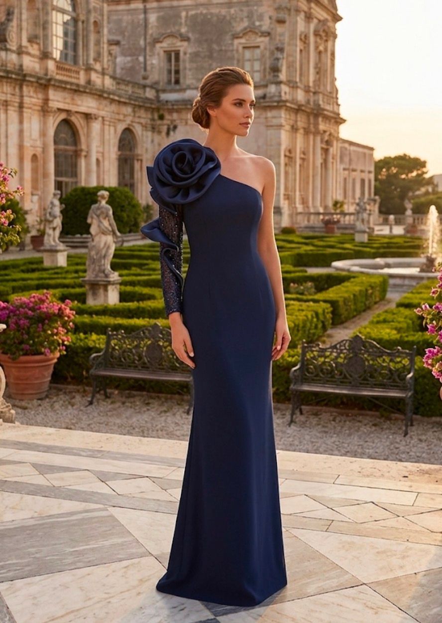 Donna in abito blu navy in piedi in un giardino formale davanti a uno storico edificio ornato