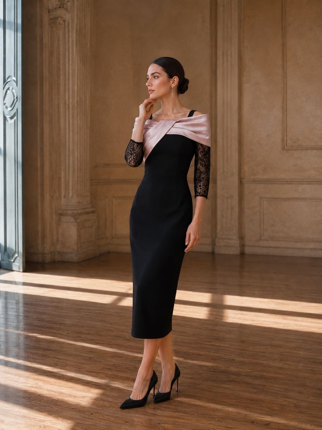 Donna con un vestito nero in piedi in una stanza illuminata dal sole, con pavimenti in legno e alte colonne.
