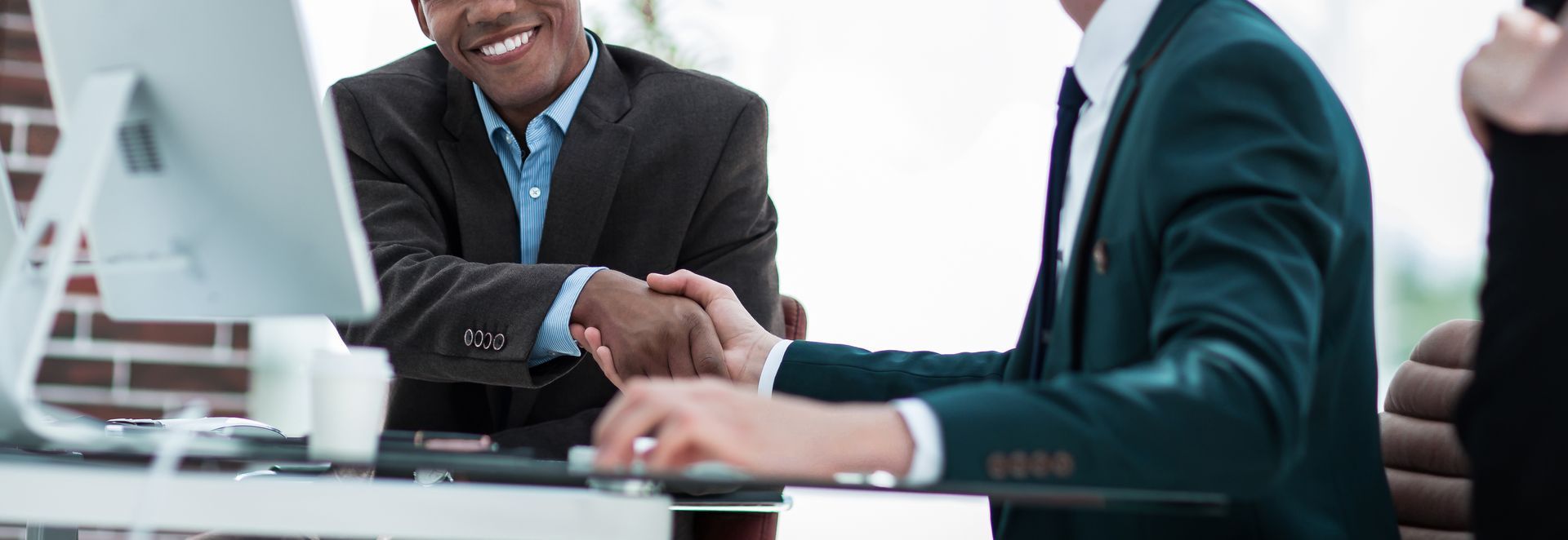 Business people shaking hands across a desk in an office setting