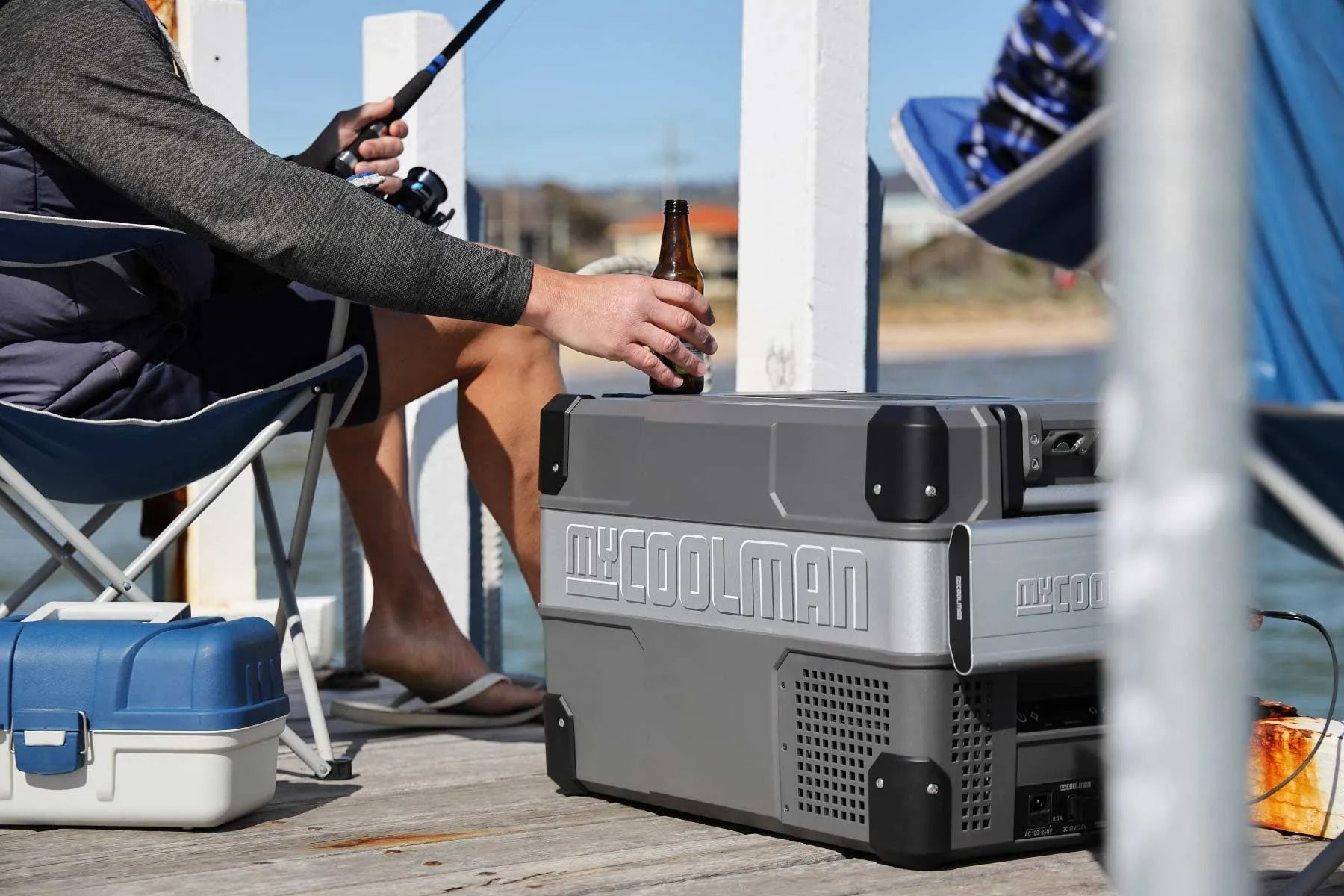 Person Reaching for a Beer From a Cooler While Fishing on a Pier — True Blue Camping Warehouse in North Mackay, QLD