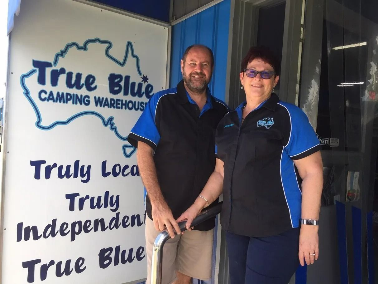 Two People, Standing in Front of a Blue Camping Warehouse Sign — True Blue Camping Warehouse in North Mackay, QLD