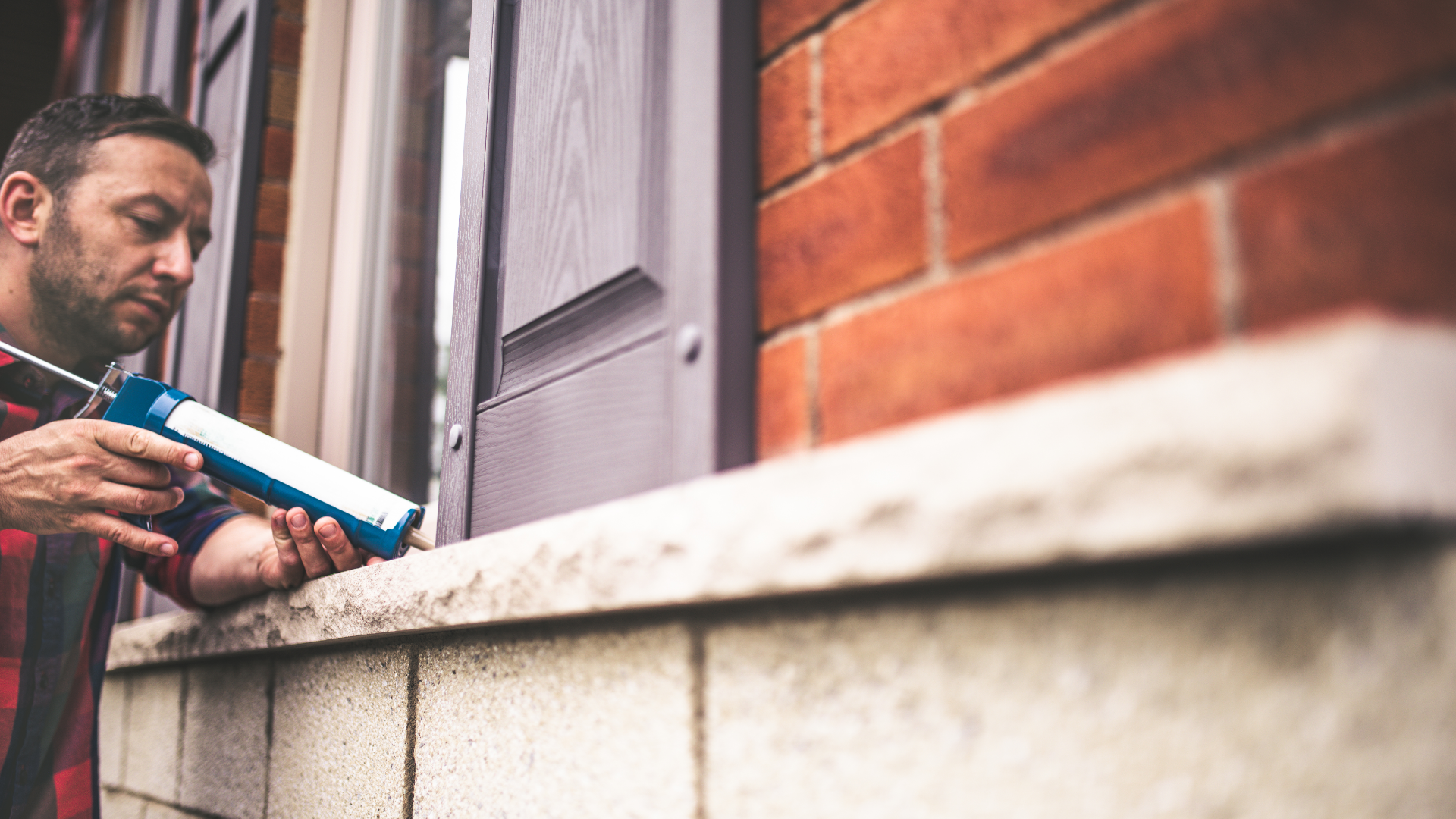 Picture of a man using flat stock caulking on a replacement window on a house in Belleville.