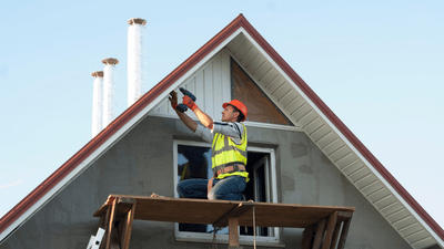 Picture of a worker repairing fascia and soffit on a house with an a-frame roof near Quinte Ontario.