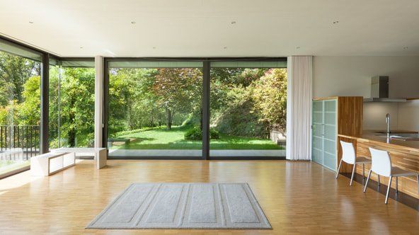 New sliding glass doors in a living room and kitchen.  The new replacement sliding doors look out into a backyard.