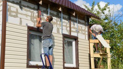 Picture of a window company in Belleville Ontario installing new vinyl siding on a house.