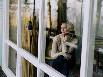 Picture of a lady looking through her new window replacement windows.  The windows have white frames.  The windows are in Quinte Ontario.