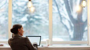 Picture of a lady looking out newly installed double hung windows in Belleville Ontario.  The windows have white frames and are replacement windows.