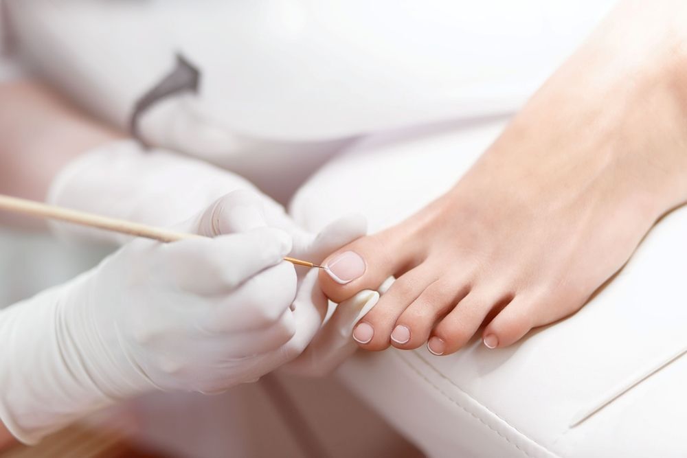 A Woman is Getting Her Toenails Painted by a Nail Artist — Craig Hughes Podiatry in Mount Hutton, NSW