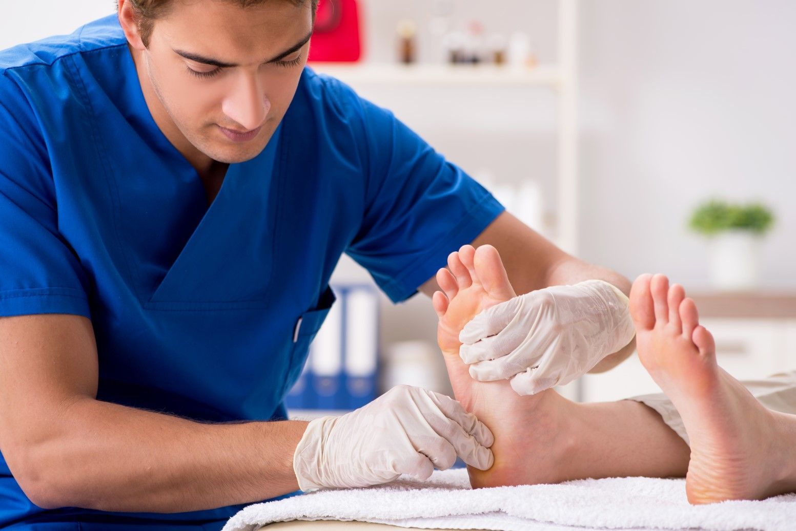 A Doctor is Examining a Patient's Foot in a Hospital — Craig Hughes Podiatry In Mount Hutton, NSW