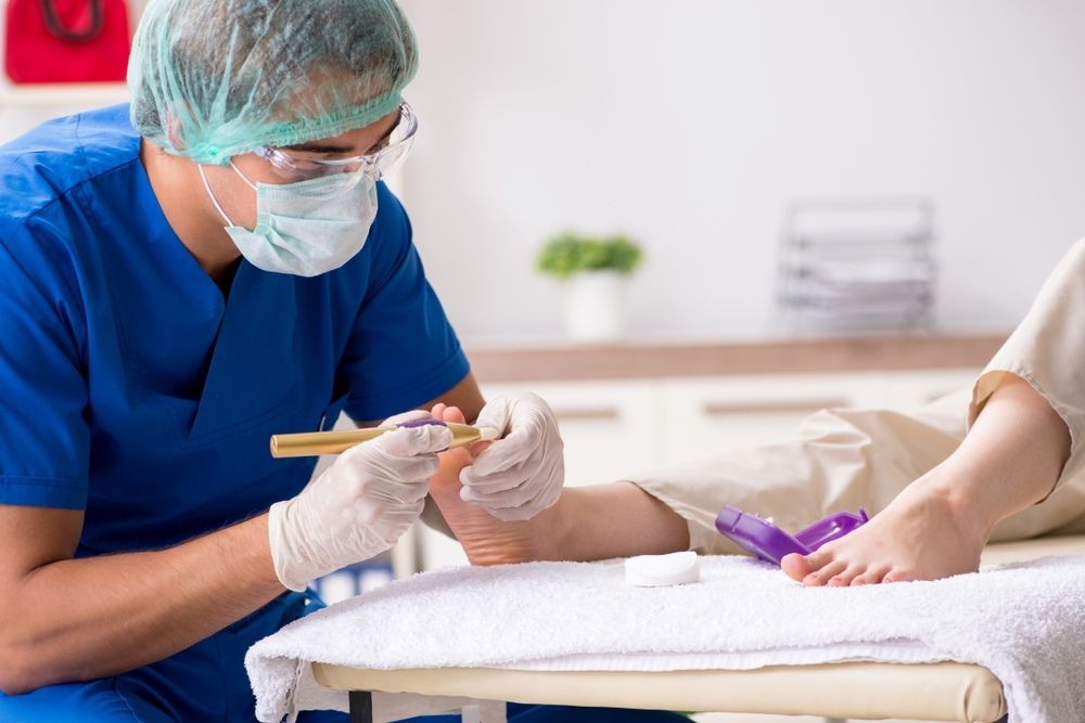 A Doctor is Examining a Patient's Foot in a Hospital — Craig Hughes Podiatry in Mount Hutton, NSW