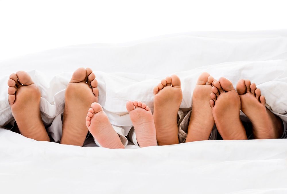 A Group of Feet Sticking Out of a Blanket on a Bed — Craig Hughes Podiatry in Mount Hutton, NSW