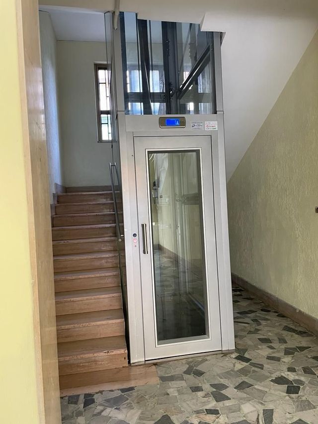 Ascensore accanto alle scale nell'ingresso di un edificio. Acciaio inossidabile con pannelli in vetro.