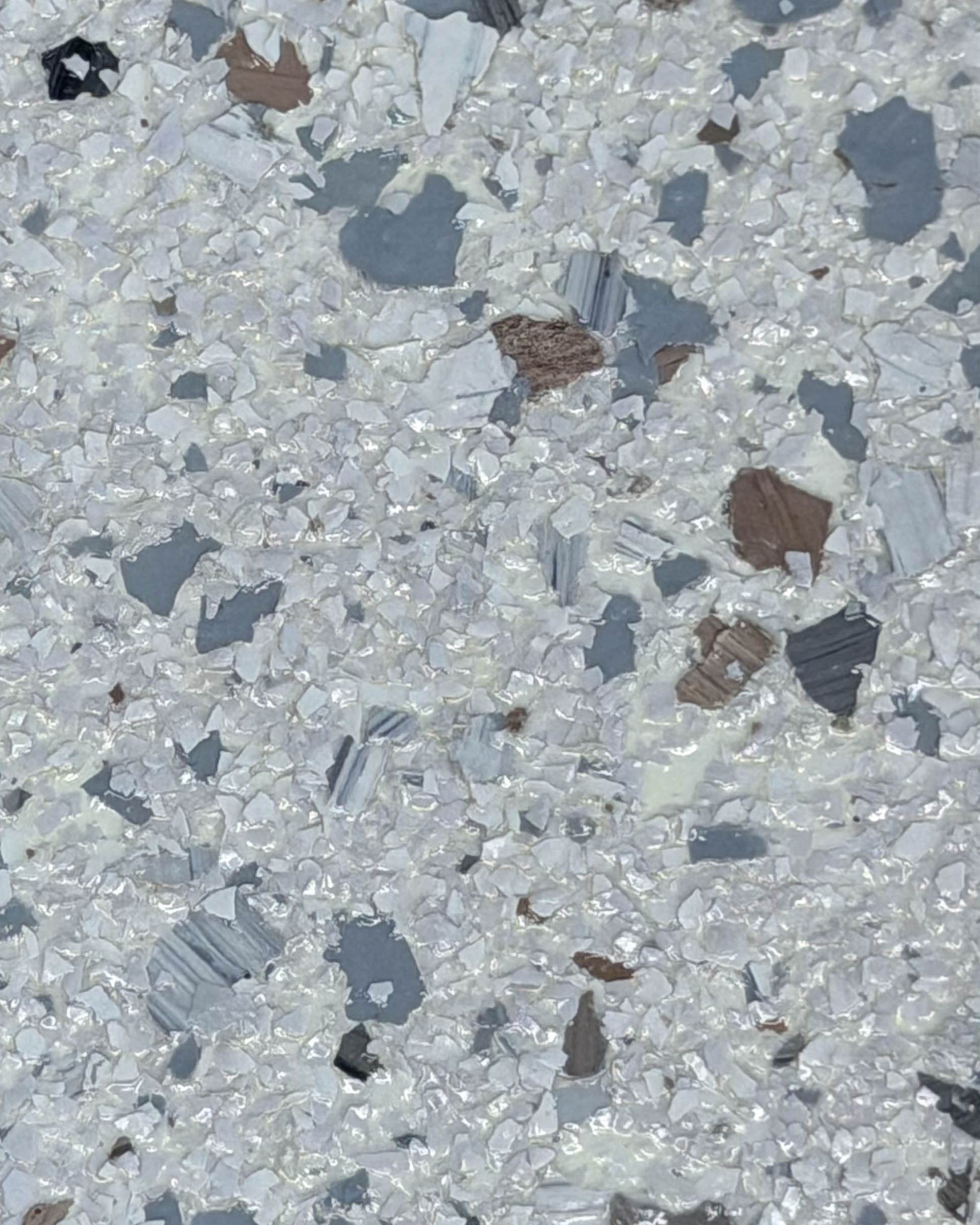 Close-up of a light gray textured surface with small darker specks and chips