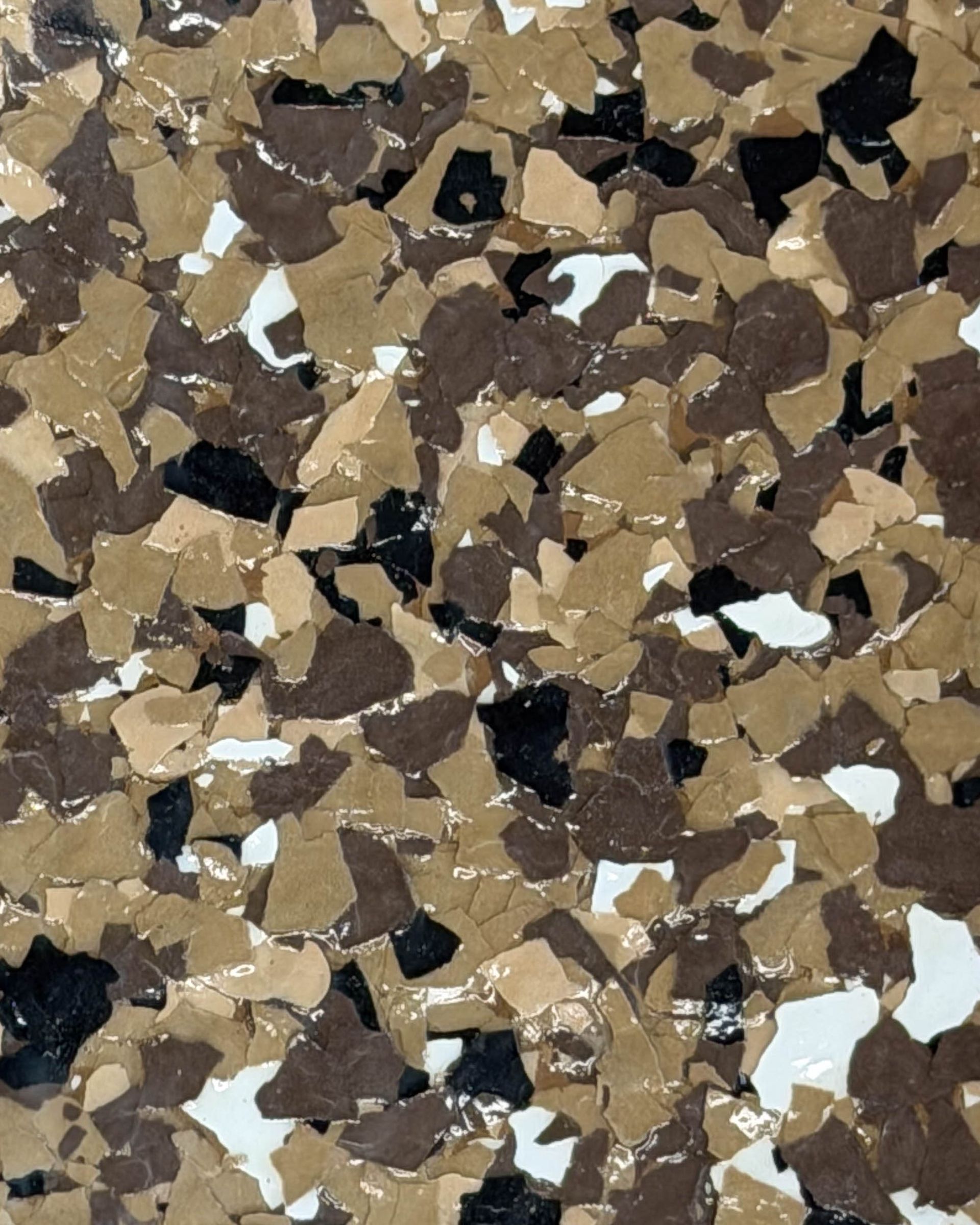 Close-up of a speckled brown, tan, black, and white stone or tile surface