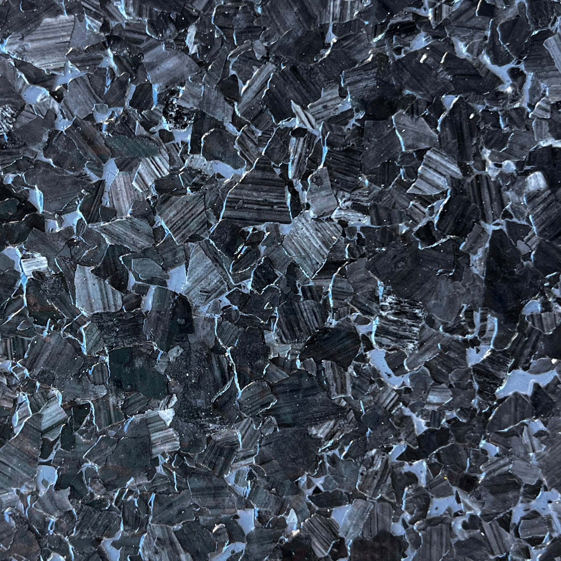 Dark blue-gray crystalline rock surface with sharp, reflective fragments