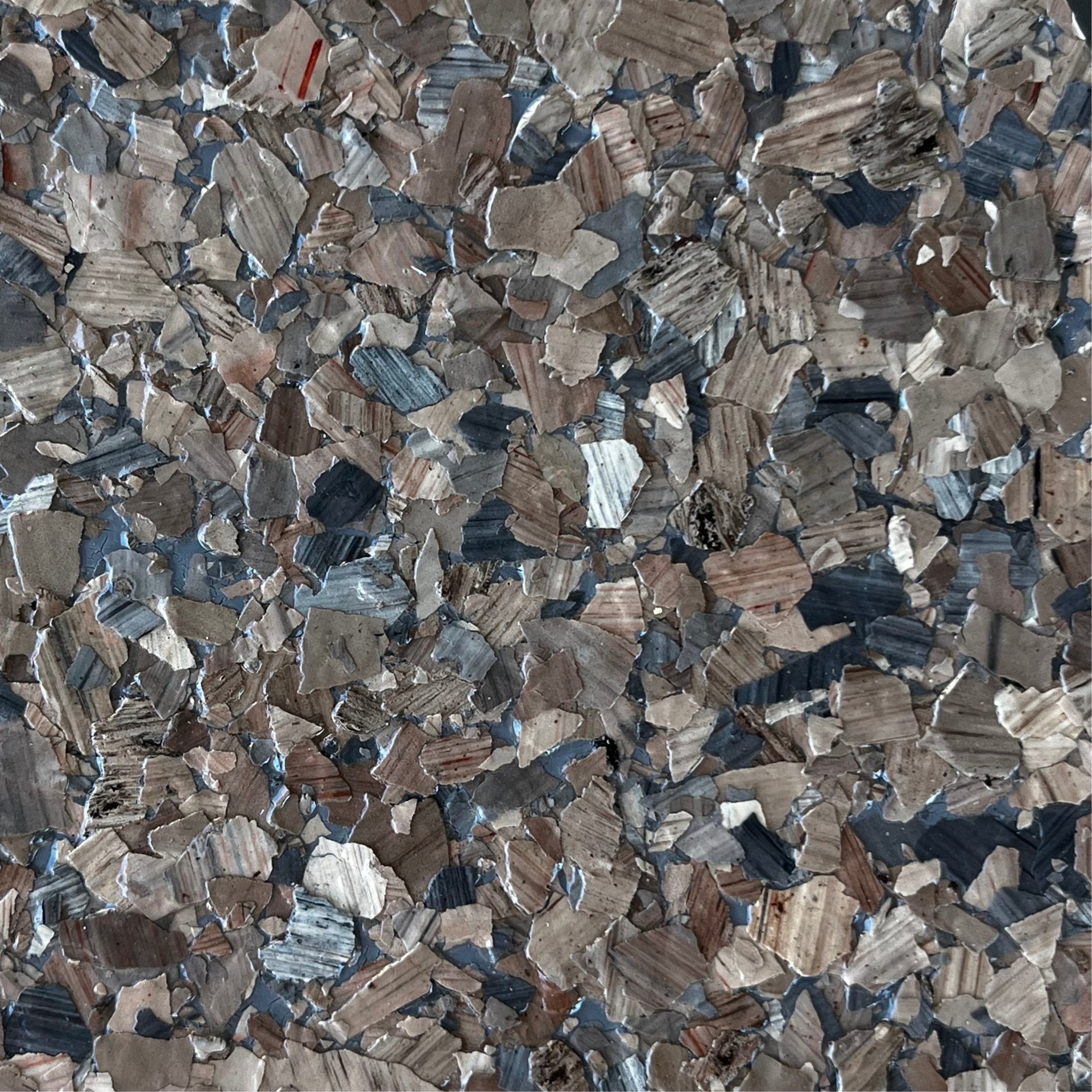 Close-up of multicolored shredded metal chips or flakes in gray, blue, and brown tones.