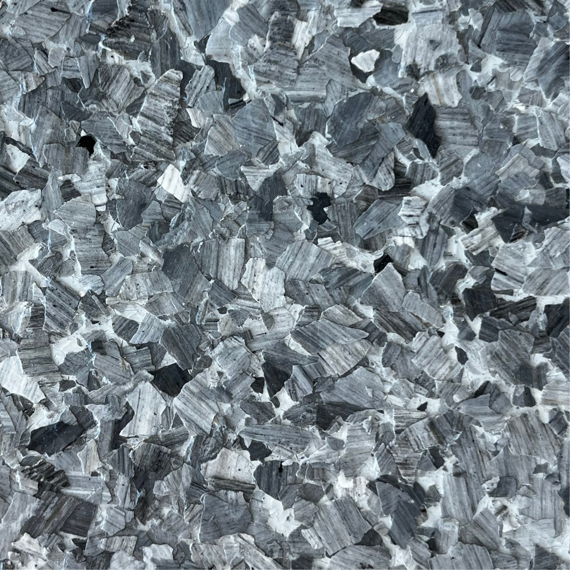 Close-up of a gray, crystalline textured surface with scattered light and dark flecks